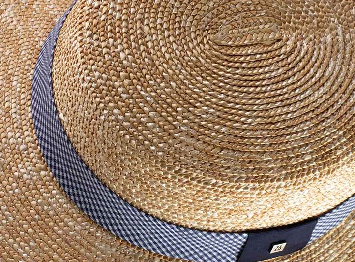 Gros plan sur un tressage spiralé cousu d'un chapeau canotier